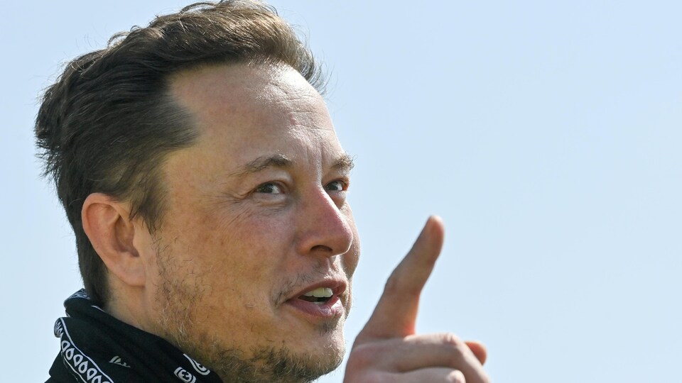 Portrait d'Elon Musk qui pointe son doigt vers le ciel.