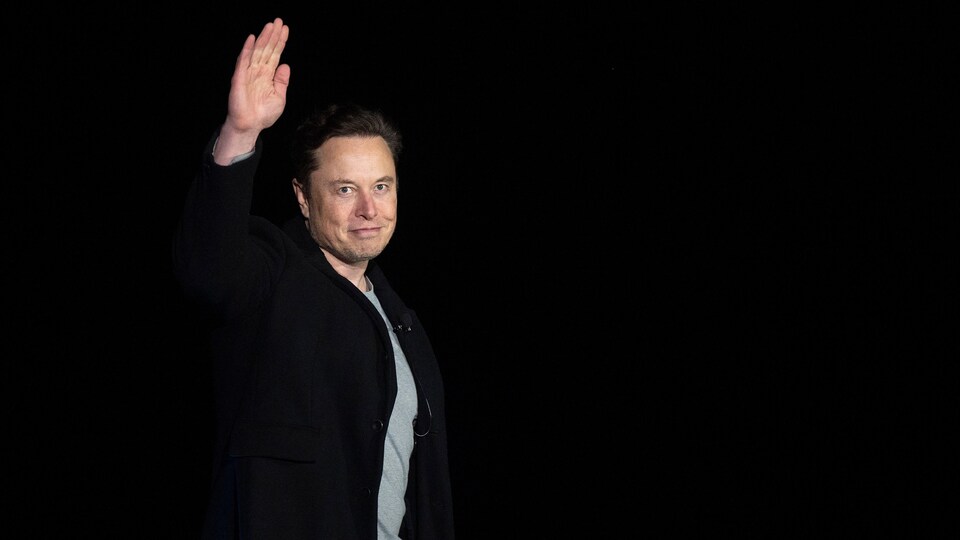 Portrait de Elon Musk en conférence de presse qui fait au revoir de la main.