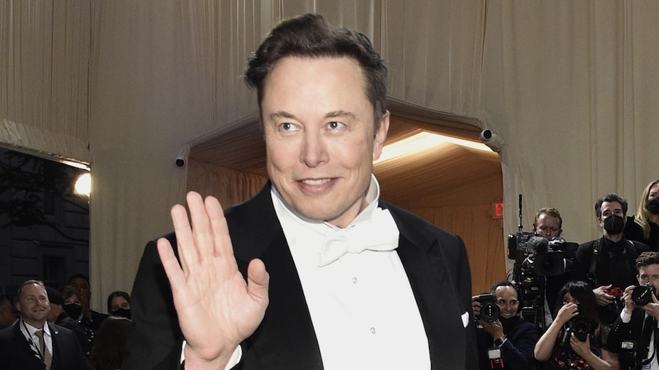 Elon Musk en tenue de soirée fait un salut de la main.