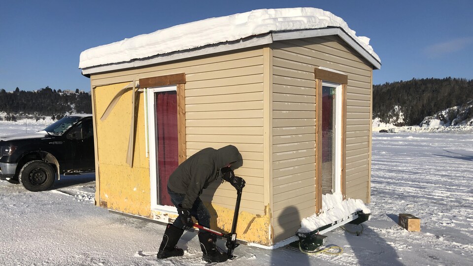 Un homme installe sa cabane sur les glaces.