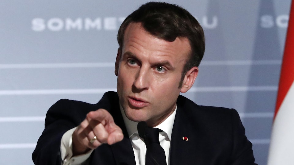 Plan rapproché du président Emmanuel Macron montrant du doigt dans le vide.