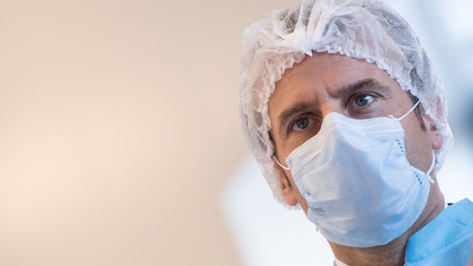 Gros plan du président Macron portant un bonnet et un masque.