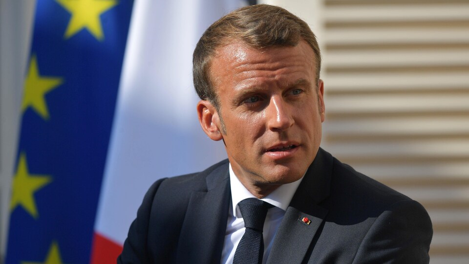 Le président français Emmanuel Macron en gros plan devant un drapeau de l'Union européenne. 