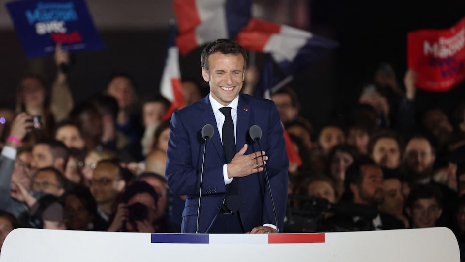 Main sur le cœur, Emmanuel Macron sourit devant ses partisans.