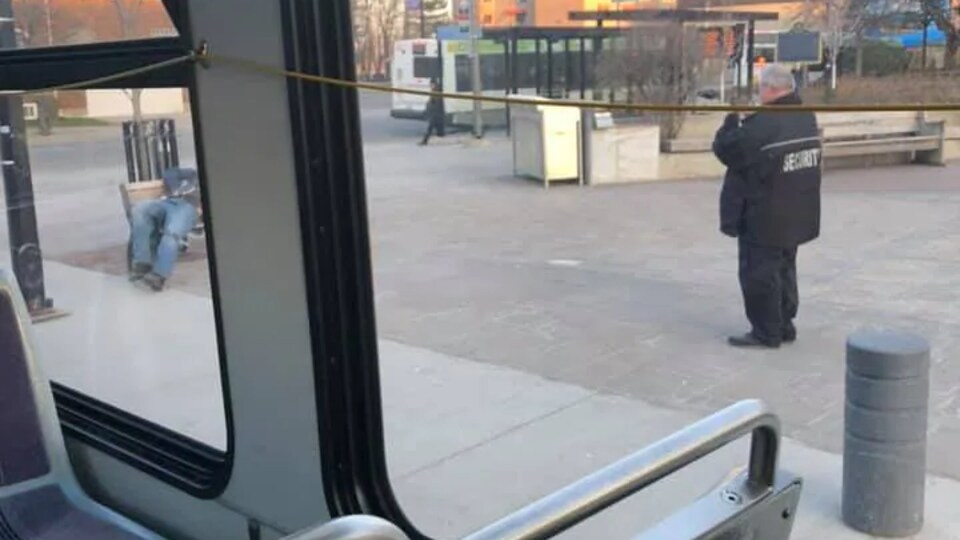 Un gardien de sécurité prend une photo de personnes sur un banc de parc.
