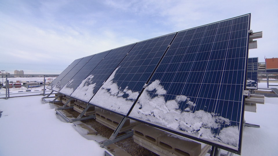Des pannaux solaires sont installés de biais. Il y a de la neige dessus et autour.