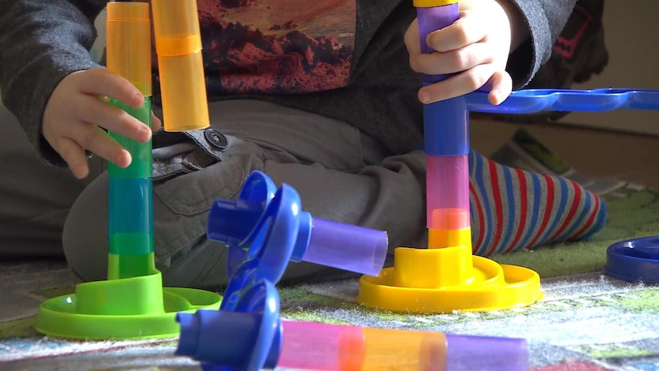 On voit seulement les mains et les jambes de l'enfant derrière le jouet.