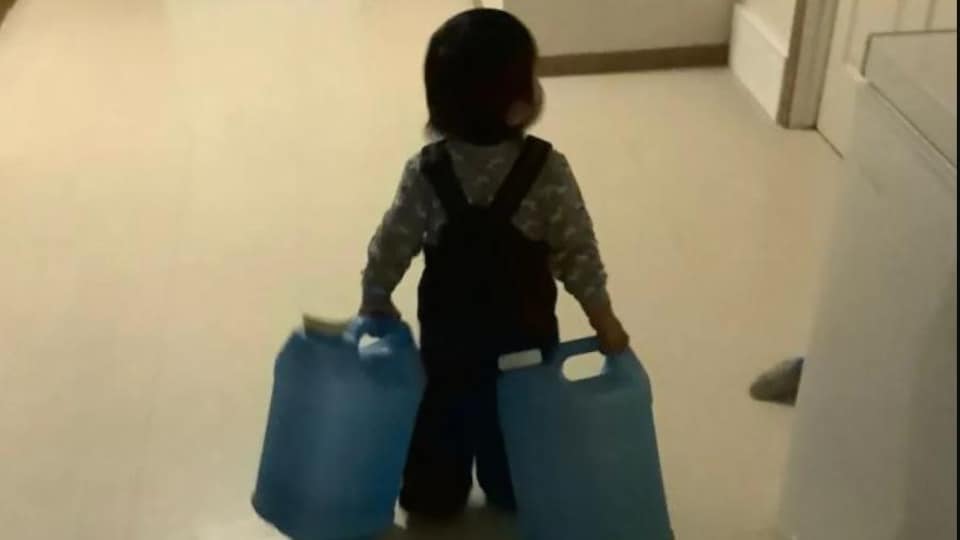 Un enfant transporte des cruches d'eau.