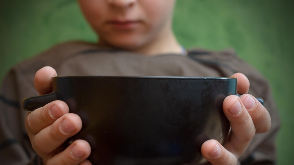 Un enfant tend un bol pour manger.
