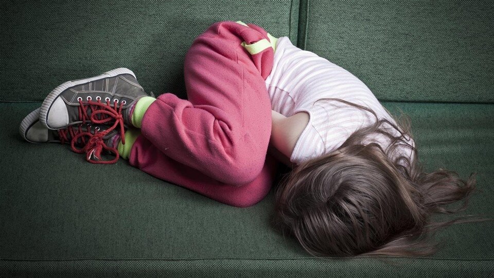 Une jeune fille est roulée en boule sur le sofa.