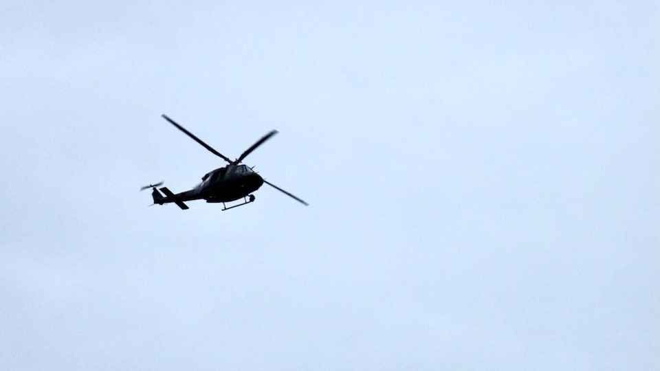 Un hélicoptère en vol dans un ciel bleu.