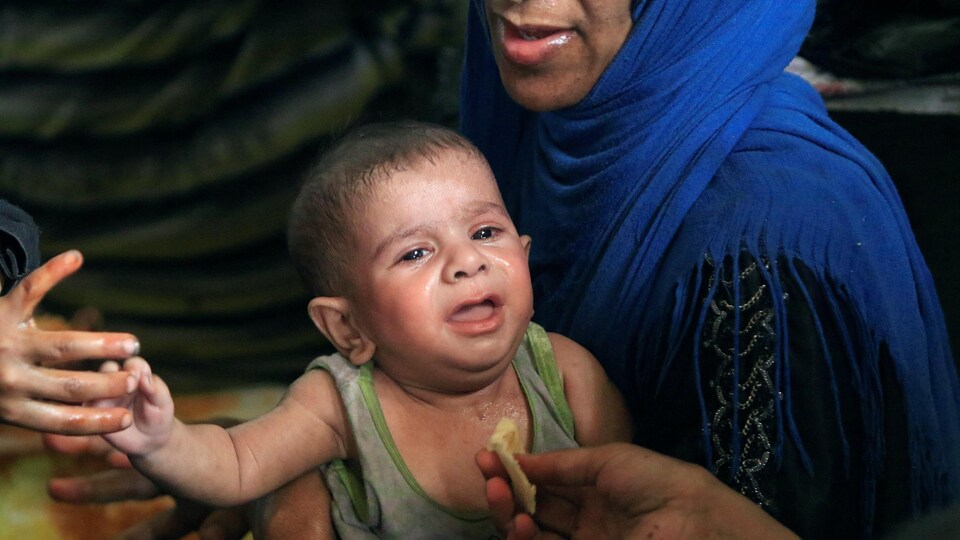 Un enfant exténué reçoit un morceau de pain à Mossoul.