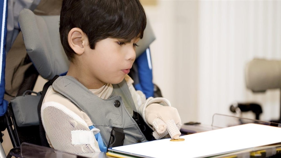Un enfant handicapé utilise un clavier tactile