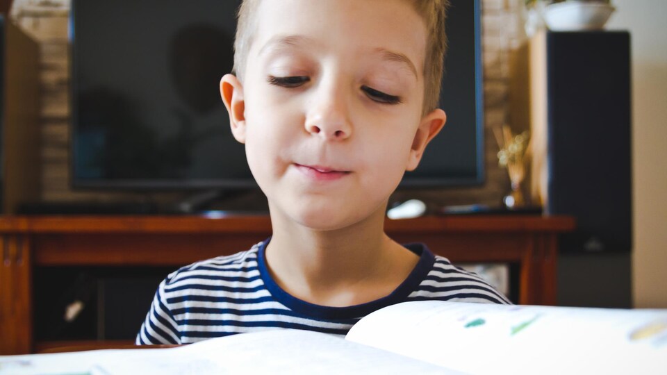Gros plan sur un enfant qui regarde un livre ouvert.