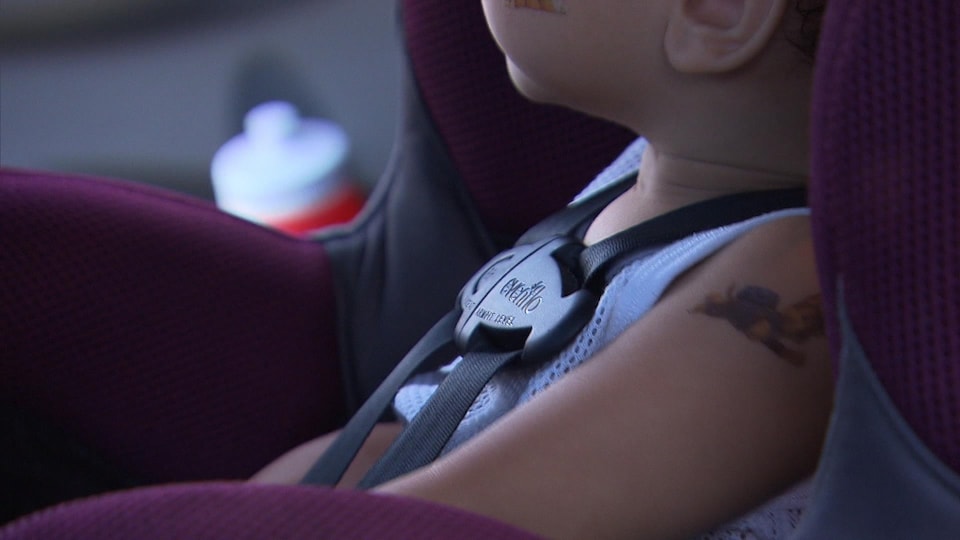 A child is sitting in a car seat with a seat belt fastened.