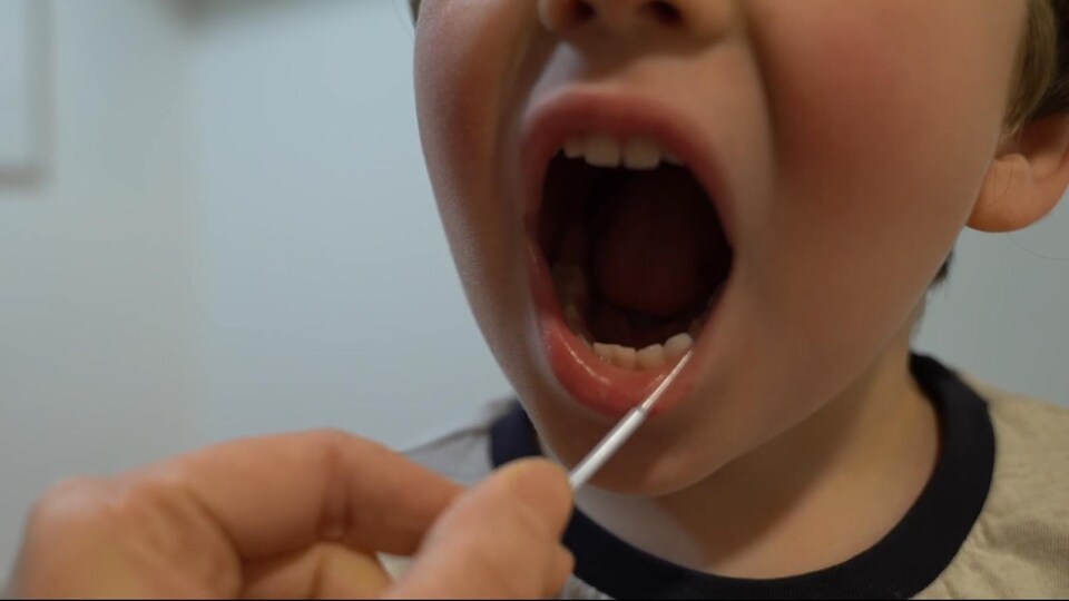 Un enfant effectue un dépistage du virus de la COVID-19 à la maison.
