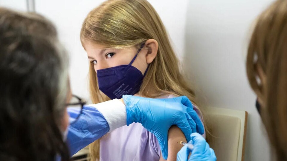 Une jeune fille se fait vacciner. 