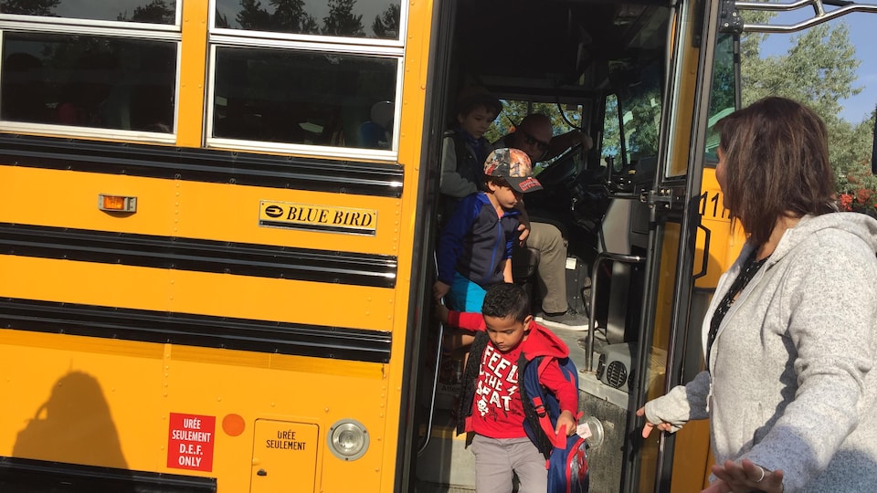 Des enfants descendent d'un autobus scolaire.
