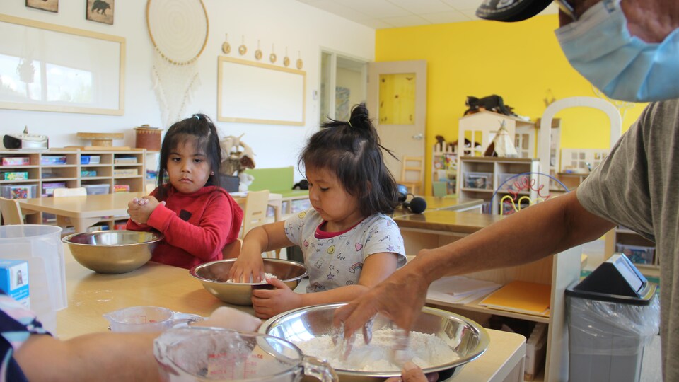 Deux petites filles mélangent de la pâte dans un saladier.