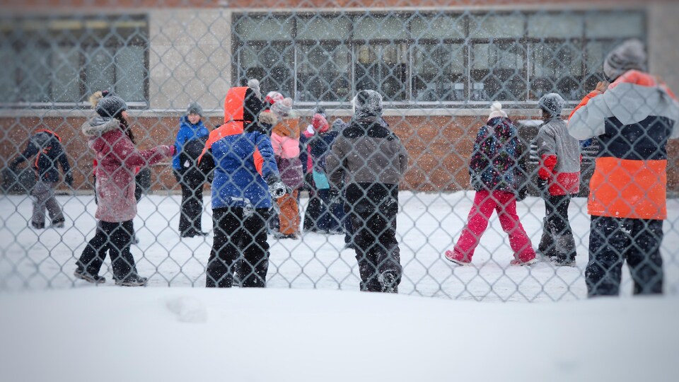 Des enfants dans une cour d'école en hiver.