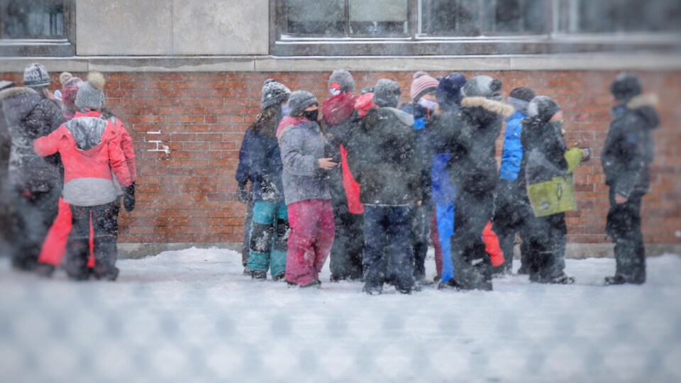Des enfants dans une cour d'école en hiver.