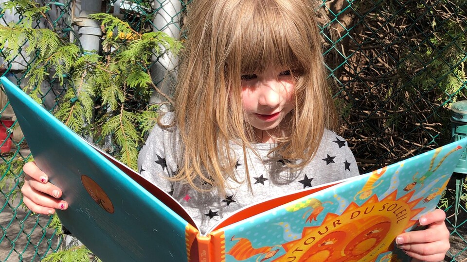 La fillette regarde un livre ouvert.
