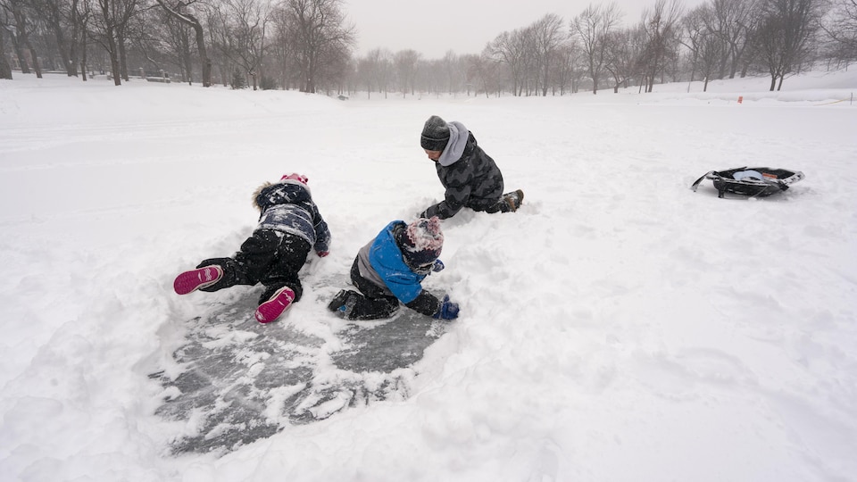Des enfants jouent dans la neige dans un parc.