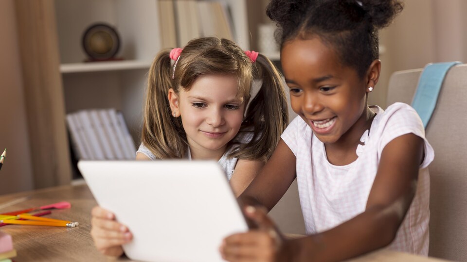 Deux jeunes filles regardent une tablette.