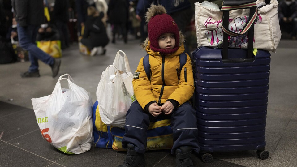 Un jeune garçon assis dans une gare.
