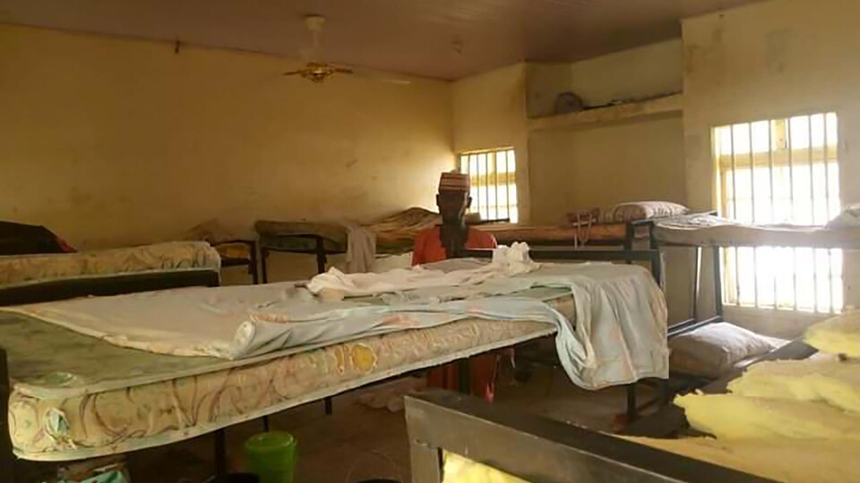 Un homme est au milieu d'un dortoir déserté.
