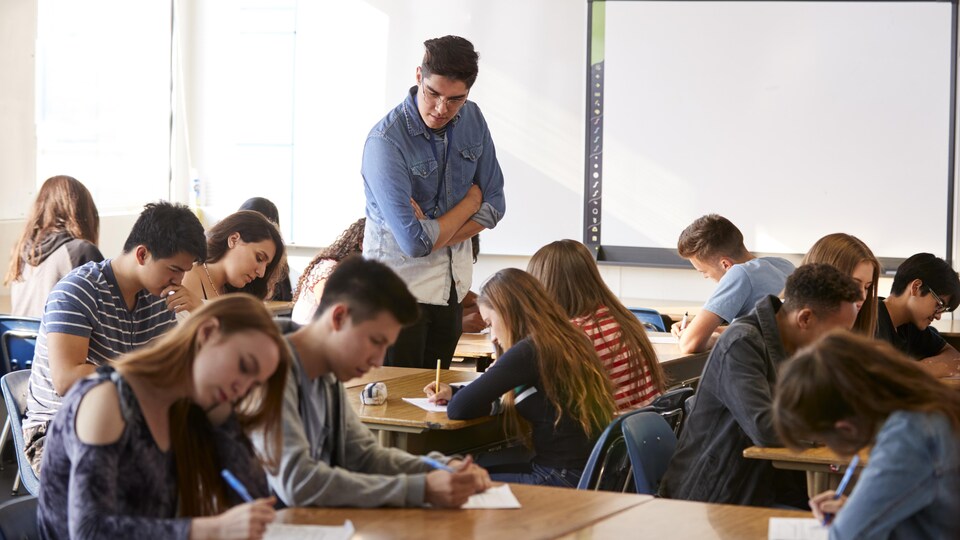 Un enseignant supervise le travail d'élèves du secondaire dans une classe.