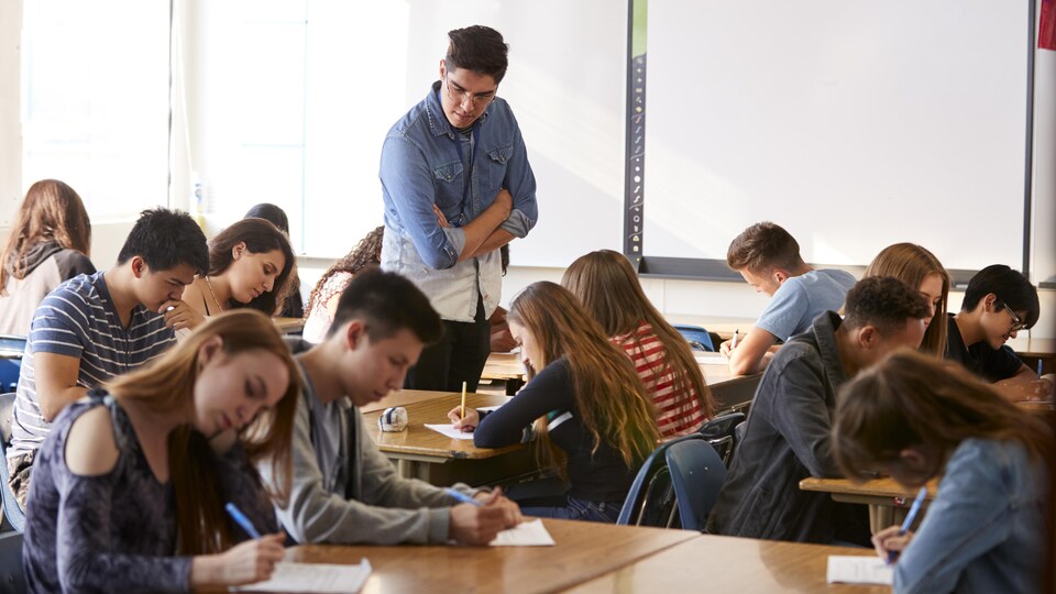 Un enseignant supervise le travail d'élèves du secondaire dans une classe.