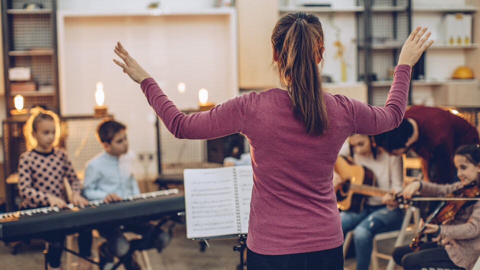 Une enseignante dirige un orchestre de jeunes