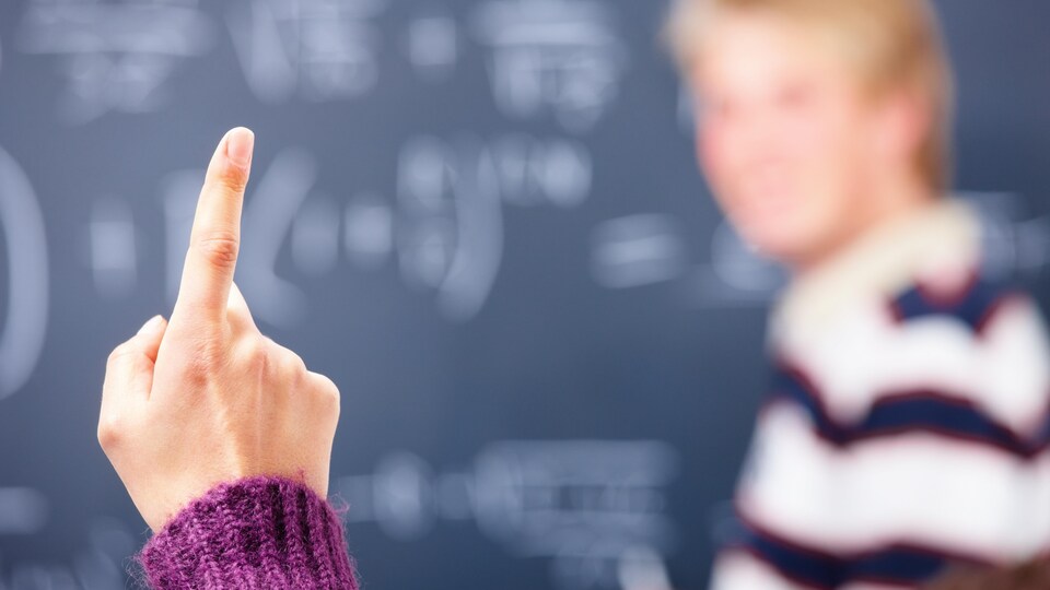 Le doigt levé d'une étudiante en classe.