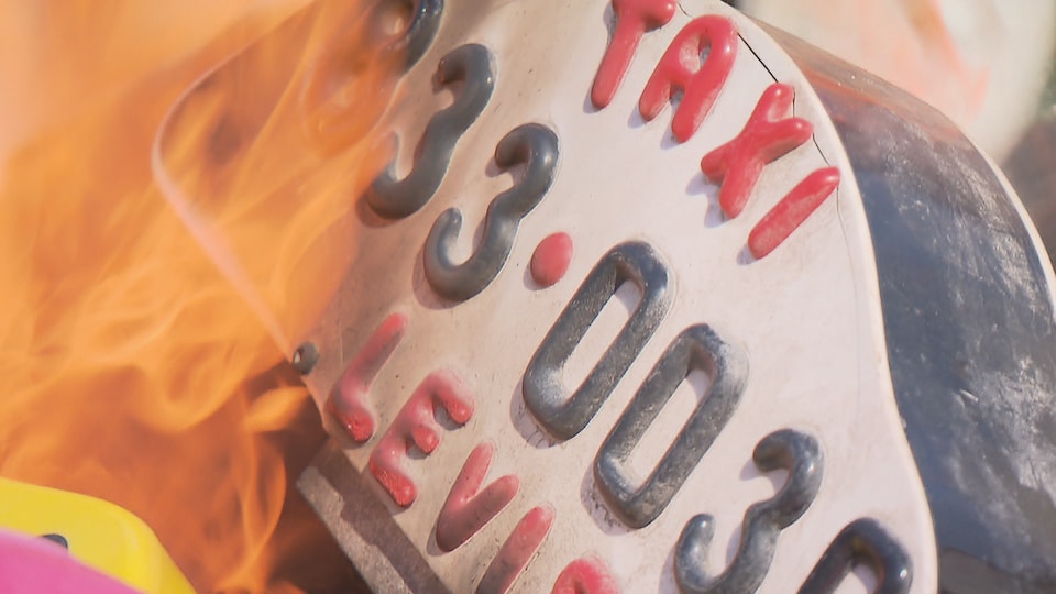 Une enseigne de taxi de Lévis en feu lors d'une manifestation à Québec