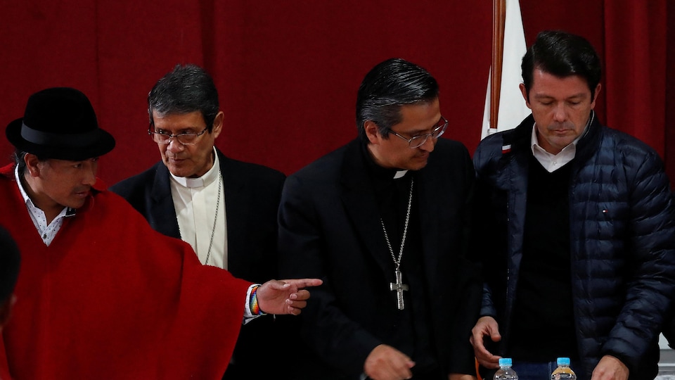 Le ministre des Finances de l'Équateur Francisco Jimenez s'apprêtant à parapher une entente avec le leader de la CONAIE sous le regard de représentants de l'Église. 