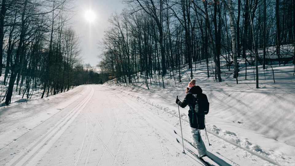 Une femme est sur une piste de ski de fond ensoleillée