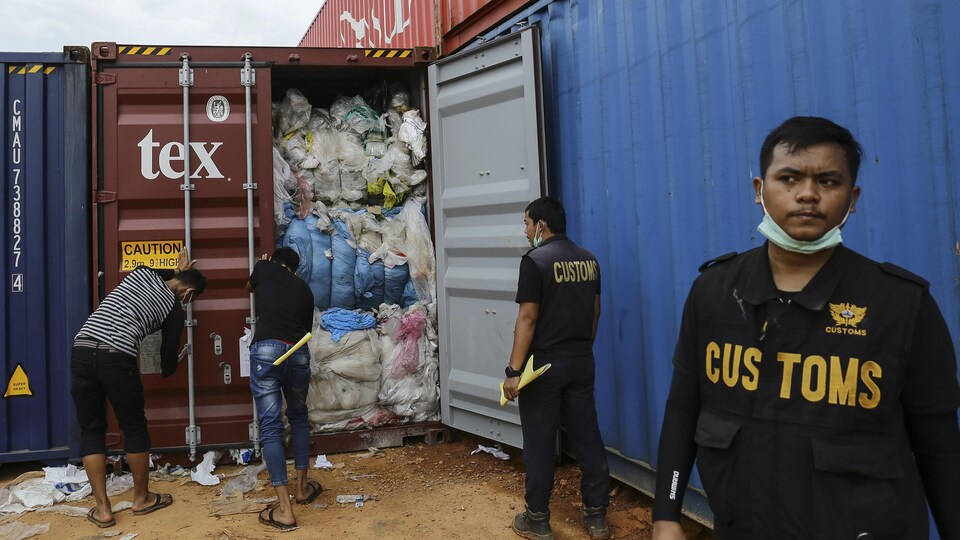 Des douaniers inspectent des conteneurs remplis de déchets plastiques.