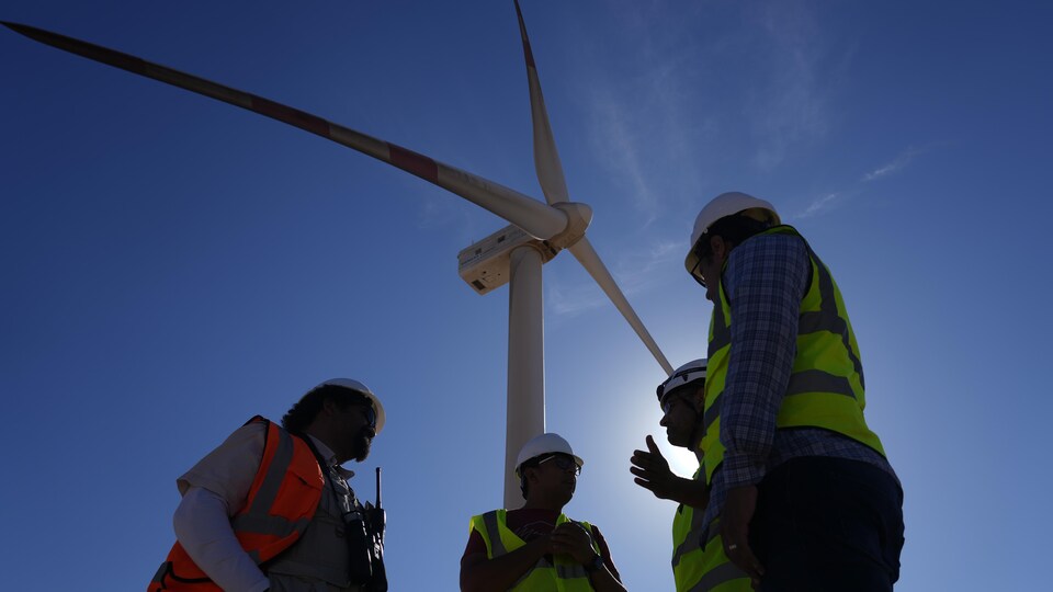 Des ingénieurs égyptiens sous une éolienne.
