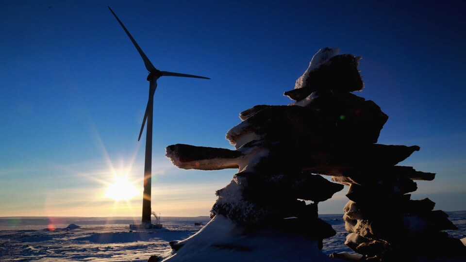 Une éolienne installée devant un inukshuk.