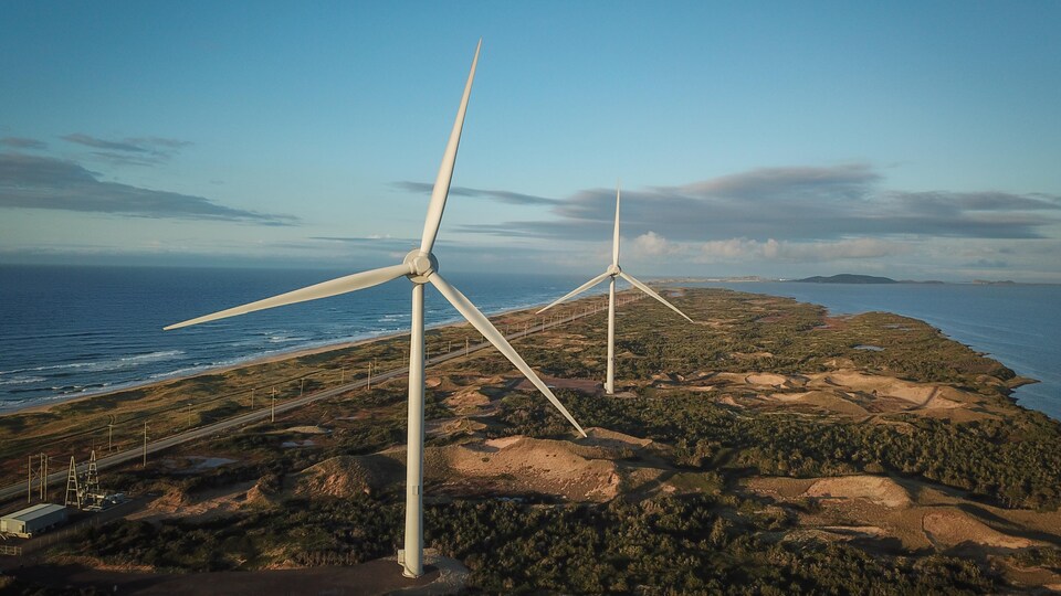 Deux éoliennes vues des airs à la pointe d'un cap. 