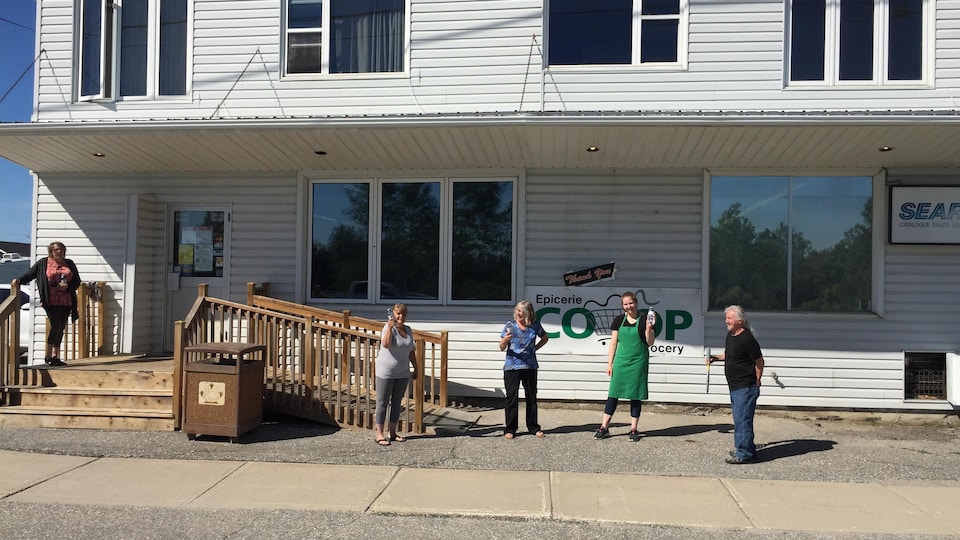 Des gens devant l'Épicerie Coop de Moonbeam.
