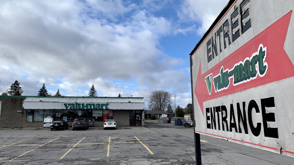Une épicerie avec quelques voitures dans le stationnement.