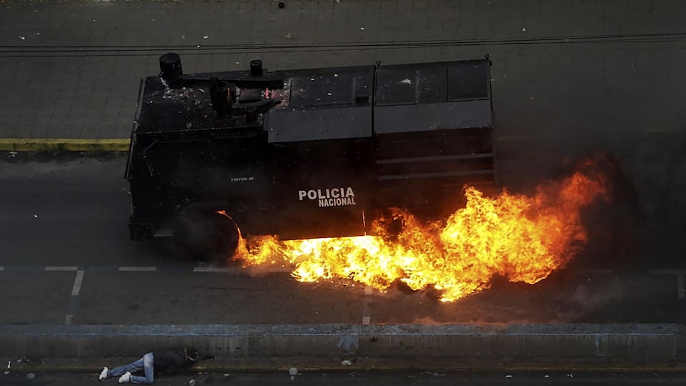 Un véhicule blindé de la police équatorienne est en feu dans une rue de Quito, lors d'une manifestation.