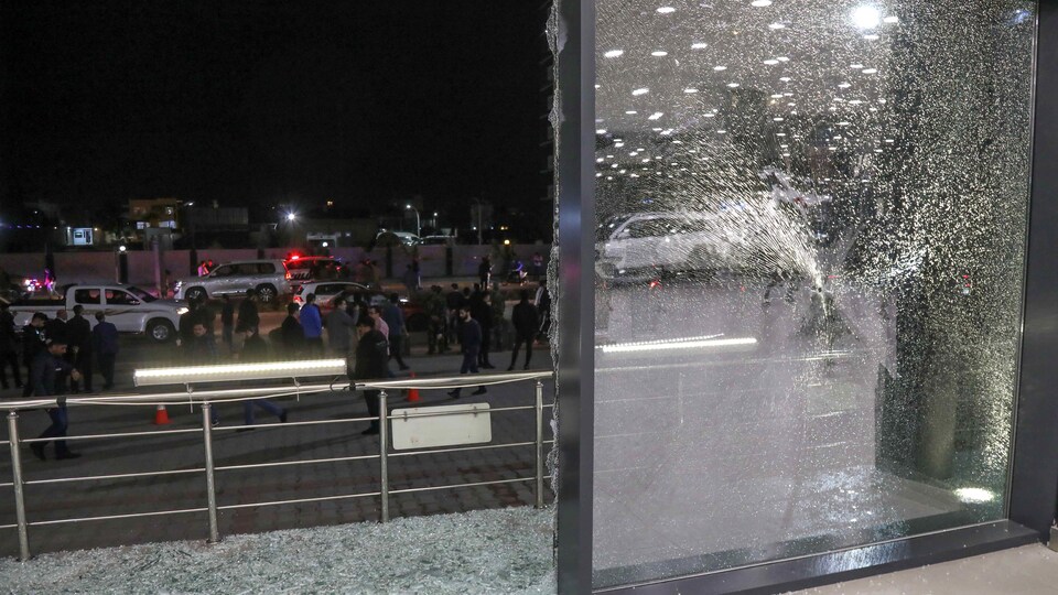 Une vitrine a été brisée par une explosion, avec en arrière-plan des passants.