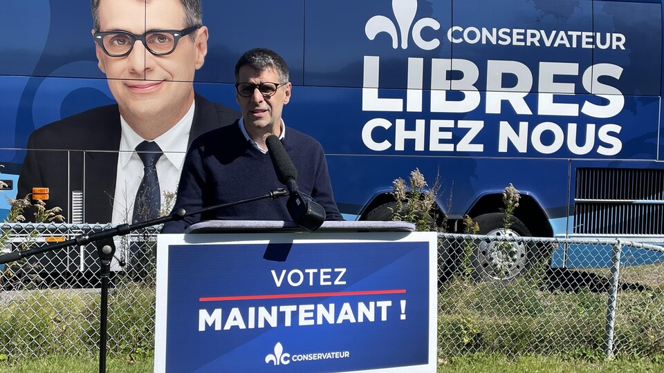 Le chef conservateur Éric Duhaime parle devant son autobus de campagne. 
