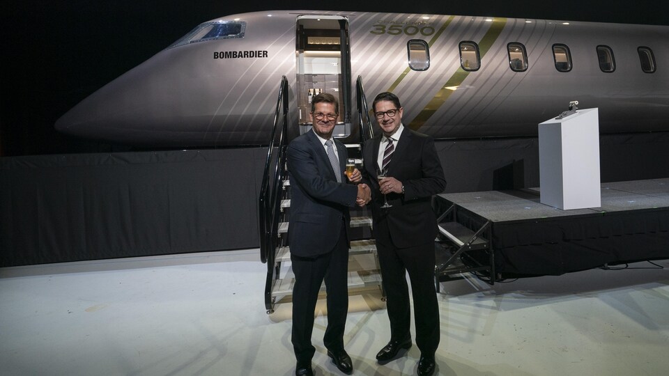 Éric Martel et Pierre Beaudoin se serrent la main devant une maquette d'avion.