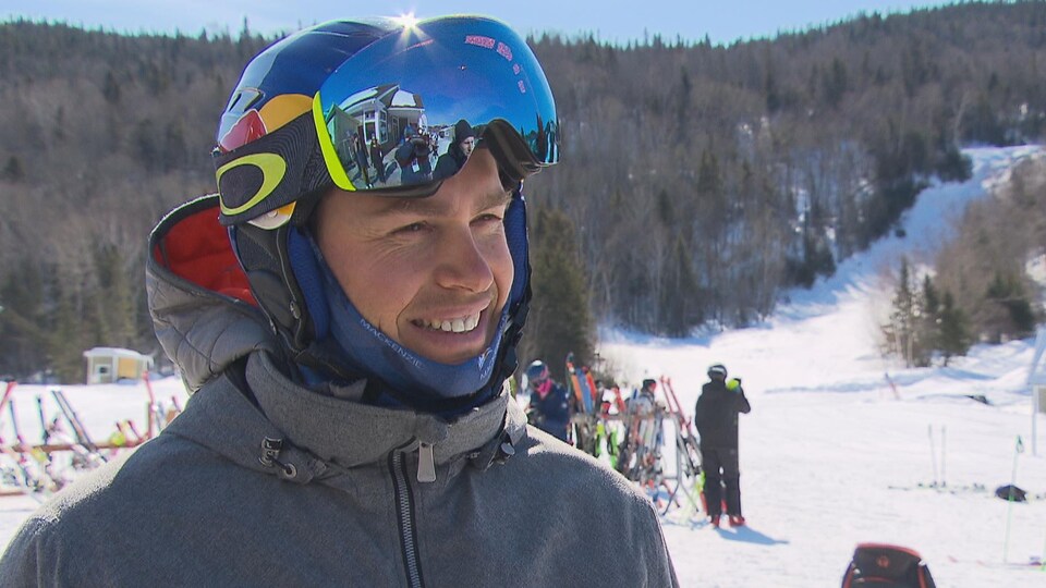 Erik Guay sourit devant les pentes d'un centre de ski.