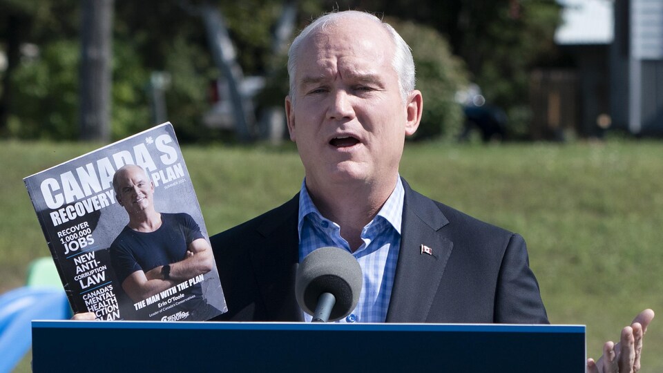 Erin O'Toole tient la plateforme électorale du Parti conservateur dans sa main.