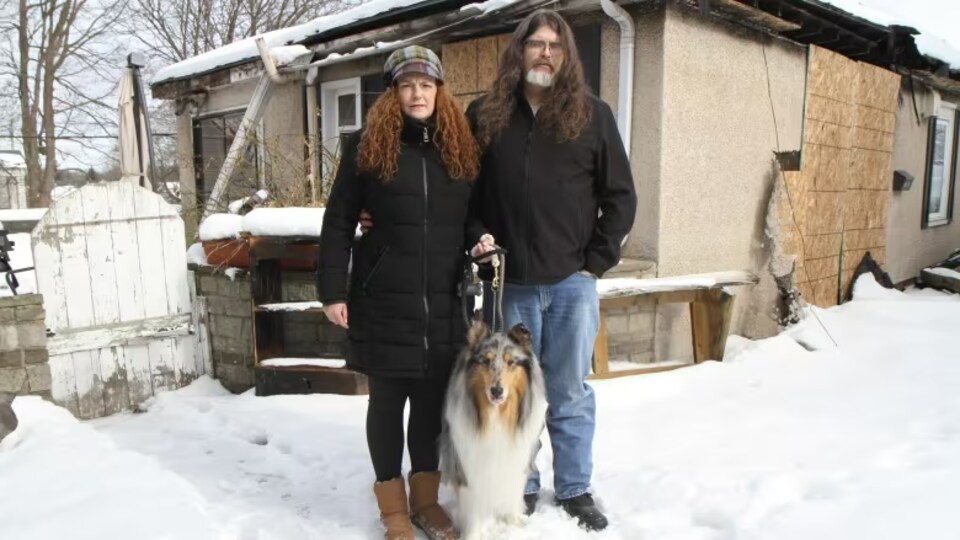 Erin Watson avec son mari et son chien devant une maison.
